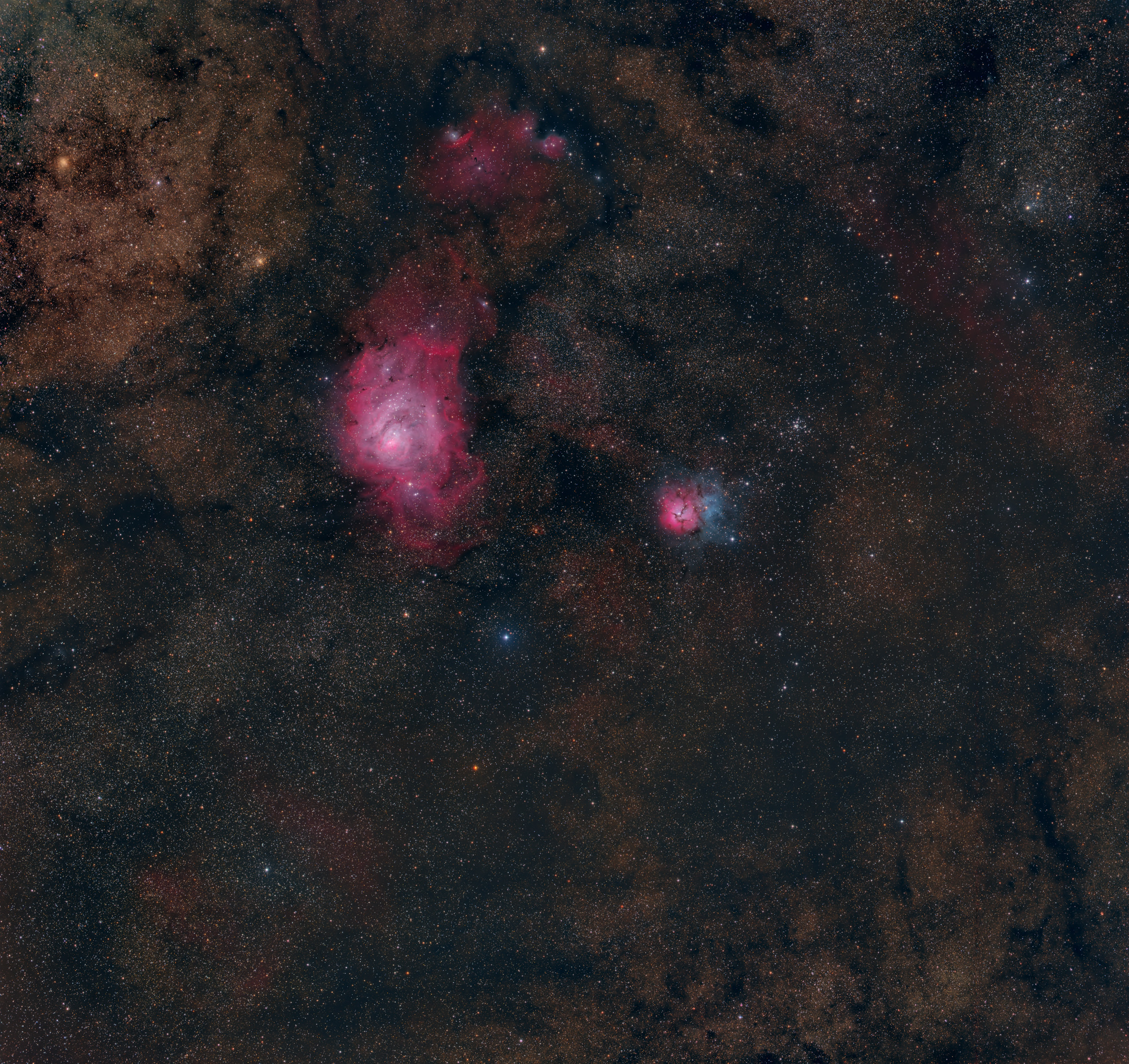Der Lagunen-Emissionsnebel Messier 8 leuchtet rot durch die Farbe von ionisiertem Wasserstoff, während der rechte Reflexionsnebel, der als Trifid Nebel Messier 20 bekannt ist, sein Blau von nahe gelegenen heißen, jungen Sternen präsentiert.